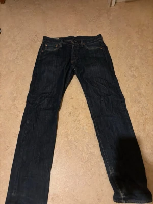 Mörkblå raka jeans från Levi's - Snygga mörkblå jeans från Levi's med klassisk rak passform och fem fickor. Jeansen har en ikonisk läderpatch bak i midjan och är gjorda i slitstark denim. Priset går att diskutera.