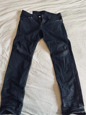 Svarta slim fit jeans - Säljer ett par svarta jeans med rak passform och klassisk femficksdesign. Jeansen har knappgylf och är tillverkade i ett slitstarkt denimtyg. Perfekta för en clean och enkel stil.