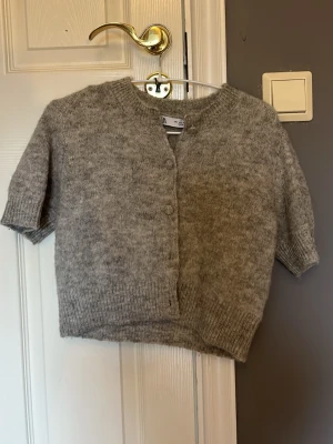 Grå kortärmad kofta från Zara  - Kortärmad grå stickad kofta från Zara med rund halsringning och ribbade muddar. 