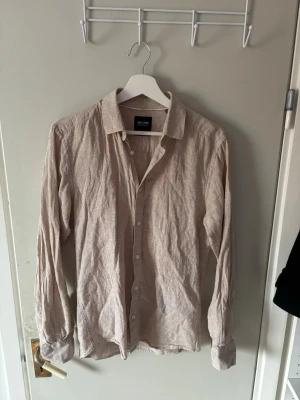 Beige linneskjorta från Only & Sons - Snygg beige skjorta från Only & Sons i luftigt linne. Klassisk krage, knappar framtill och långa ärmar med knapp vid manschetten. Perfekt för dig som gillar en avslappnad men stilren look.