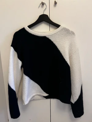 Svartvit stickad tröja Gina Tricot - Säljer en snygg stickad tröja från Gina Tricot i svart och vitt med breda diagonala blockränder. Tröjan har rund halsringning, långa ärmar och är gjord i ett mjukt, fluffigt material. Perfekt för dig som gillar en trendig och avslappnad stil.