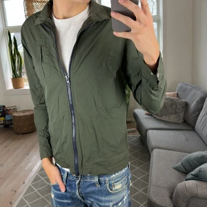 Fieldjacket Olivgrön - Grön fältjacka i clean och hållbar design  Tidlös look med fokus på kvalitet och stil. Sitter snyggt och funkar året runt   📏 Storlek: M ⚡️ Mycket bra skick 💰 400 kr  A:49cm B:44cm C:46cm D:62cm (Tunn jacka)