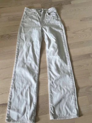 Vita raka jeans från Maison Margiela - Snygga vita jeans från Maison Margiela med rak passform och klassisk femficksdesign. Jeansen har hög midja, bälteshällor och stängs med knappar. Perfekta för en clean och trendig look.