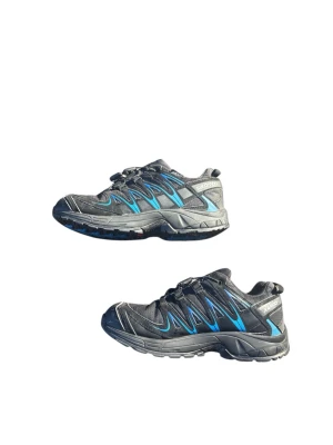 Svarta Salomon sneakers med blå detaljer - Säljer ett par svarta Salomon sneakers med blå och grå detaljer. Skorna har en sportig design, snabbsnörning och robust sula för bra grepp. Ovandelen är i slitstark textil och syntet, perfekt för en aktiv livsstil.