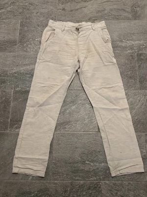 Beiga linnebyxor med raka ben - Snygga beiga linnebyxor med raka ben och klassisk passform. Byxorna har fickor fram och hällor för skärp i midjan. Perfekta för en avslappnad och stilren look. Materialet är lätt och luftigt linne som passar bra till varmare dagar.