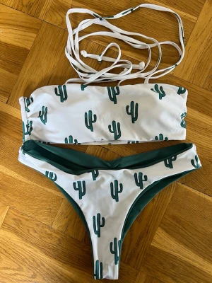 Vit/grön bikini med kaktusmönster - Snygg bikini från Zaful med bandeau-topp med långa snören att knyta. Trosorna är vändbara, går att ha både gröna och vita med kaktus. 
