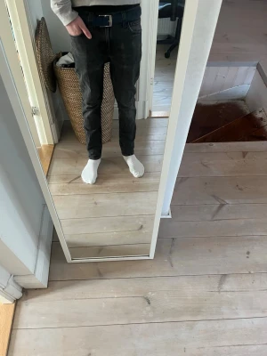 Svarta slim fit jeans - Säljer ett par svarta slim fit jeans med klassisk femficksdesign och bälteshällor. Jeansen har en rak passform och är tillverkade i ett mjukt denimtyg som sitter snyggt på benen. Perfekta för dig som gillar en stilren och enkel look. Endast en defekt litet hål vid skrevet men de e enkelt o sätta ihop me lite tråd 