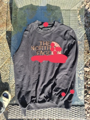 Svart sweatshirt från The North Face o gg - Säljer en svart sweatshirt från The North Face gg med stort logotryck i brunt och beige på bröstet. Tröjan har rund halsringning, ribbade muddar vid ärmslut och nederkant samt en avslappnad passform. Perfekt för en casual och sportig stil. Riktiga bilder går o lösa
