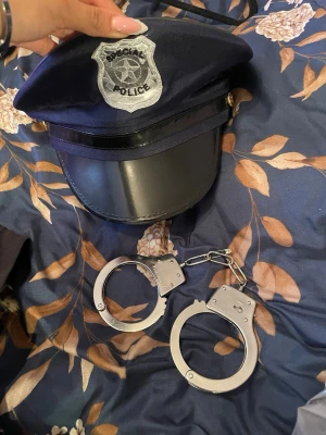 Polis kostymkit med keps och handbojor - Säljer ett maskeradkit med en mörkblå polis-keps med silverfärgad badge där det står 'Special Police' samt ett par silvriga handbojor i metall-look. Perfekt för maskerad eller cosplay som polis. Finns en liten smink fläck på hatten och nyckeln till handbojorna är borta men de går ändå att öppna och låsa dem.