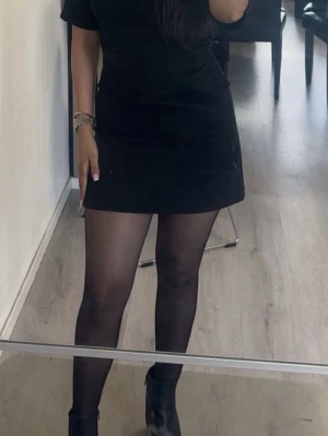 Svart kortkjol i enkel design - Snygg svart kortkjol med rak passform och minimalistisk stil. Kjolen är enfärgad och passar perfekt till många olika outfits. Tillverkad i ett mjukt material som ger en bekväm känsla. Perfekt för dig som gillar stilrena plagg.