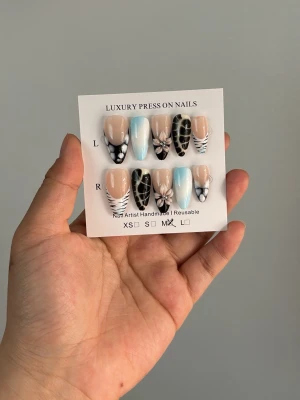 Handgjorda press-on naglar med 3D-blomma - Snygga handgjorda press-on naglar i mandelform med mixade designer i svart, blått, vitt och nude. Några naglar har 3D-blomdetaljer och andra har coola mönster som zebra och fjäril. Perfekt för dig som vill ha unika och trendiga naglar. Återanvändbara .