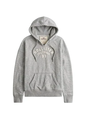 Grå hoodie från Hollister california 22 ”sällsynt” - Snygg grå hoodie från Hollister med broderad text 'Hollister California 22' på bröstet. Klassisk känguruficka framtill, ribbade muddar och justerbar huva med dragsko. Mjuk insida och avslappnad passform, perfekt för chill dagar.