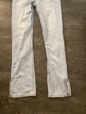 Ljusblå bootcut jeans med slits från Nelly  - Säljer ett par ljusblå bootcut jeans med slitsar nertill på benen. Jeansen har klassisk femficksdesign och är tillverkade i denim. Perfekta för en avslappnad och trendig look.