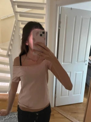 Ljusrosa offshoulder topp med öppen rygg - Trendig ljusrosa topp med offshoulder-design och korta ärmar. Baksidan har en cool öppen rygg med tunna band som ger en edgy look. Tillverkad i mjukt bomullsmaterial och sitter snyggt med en normal passform. Perfekt för dig som vill sticka ut lite extra. Denna har jag gjort själv och det är sååå mjukt matrial💞