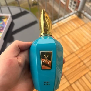 Xerjoff Erba Pura parfym 100ml - Lyxig parfym från Xerjoff, modell Erba Pura. Flaskan är turkosblå med guldfärgat lock och detaljer. Unik, elegant design med en metallplatta framtill och logotyp. Kommer i en färgglad presentförpackning. Perfekt för dig som gillar exklusiva dofter.