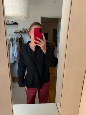 Svart skjorta med vida ärmar - Säljer en svart skjorta med avslappnad passform och vida ärmar. Skjortan har klassisk krage och knäppning framtill. Stor i storleken