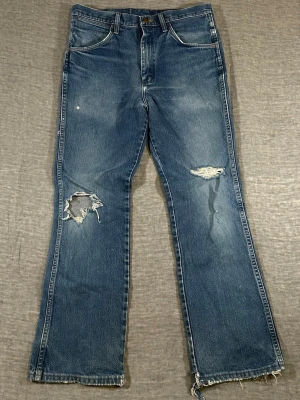 Vintage 2000s Wrangler 935NAV Distressed Flare Jeans W32 L31 - Wrangler 935NAV vintage 2000s jeans in a perfect worn-in wash 🔥 Tagged W34 L32 but fits closer to W32 L31. Mid rise straight fit with slight flare — super on trend. Natural fading + distressed knees gives that real Y2K vintage look.  waist 41 cm, inseam 74.5 cm, thigh 27 cm, knee 21 cm, foot 22 cm measure your favorite jeans the same way to compare fit  Used condition with visible wear, distressing and frayed hems, still strong denim
