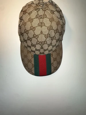 Gucci keps äkta – kvitto finns – helt ny - Säljer en 100% äkta Gucci keps som jag fick i present. Den är inköpt på Istanbul Airport och kvitto finns som bevis på äkthet.  Kepsen är i mycket fint skick (helt ny ungefär ), men jag använder tyvärr inte kepsar så den blir bara liggande – därför säljer jag den hellre.  • Äkta Gucci • Kvitto finns • Mycket bra skick • Endast använd få gånger  Pris kan diskuteras vid snabb affär. Hör av dig vid frågor!