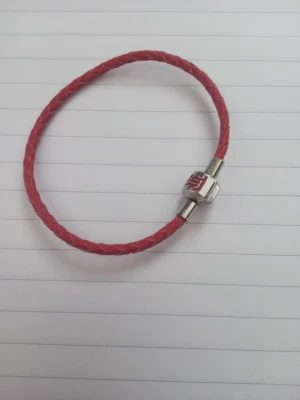 Rött armband - Snyggt armband i rött flätat läder med  silverfärgad metall där det står 'Hej' i rött. Notera att den är liten i storleken.