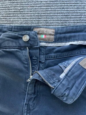 Mörkblå jeans från Cavaliere - Snygga mörkblå jeans från Cavaliere med klassisk femficksdesign och raka ben. Jeansen har en diskret logotyp på insidan och detaljer som metallknapp och dragkedja. Materialet är mjukt och stretchigt för extra komfort.