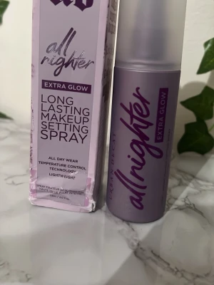 Urban Decay All Nighter Extra Glow - Urban Decay All Nighter Extra Glow är en lila makeup setting spray som ger extra glow och håller sminket på plats länge. Flaskan är smidig och lätt, med modern design och sprayfunktion. Perfekt för dig som vill ha en fräsch och hållbar finish.