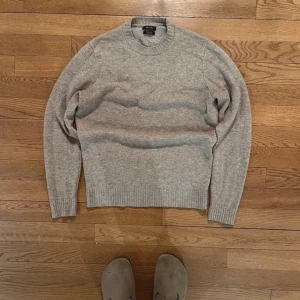 Grå stickad tröja från Massimo Dutti - Säljer en stilren grå stickad tröja från Massimo Dutti i mjukt material. Tröjan har rund halsringning och ribbstickade muddar vid ärmslut och nederkant. Perfekt för lager-på-lager och enkel att matcha med jeans eller chinos.