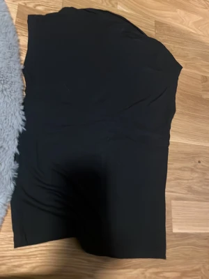 Svart ärmlös topp från 157 - Svart enkel och stilren topp från 157 i storlek S. Modellen är ärmlös och har en tight passform som sitter snyggt på kroppen. Perfekt att matcha med jeans eller kjol för en clean look.