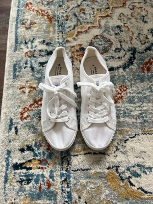 Vita låga sneakers från race Marine - Klassiska vita sneakers från race marine i canvasmaterial med vita snören och gummisula. Modellen är låg och har en stilren, minimalistisk design som passar till många olika outfits. Perfekta för dig som gillar en clean och enkel look.