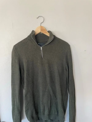 Olivgrön stickad tröja med halvzip - Snygg olivgrön stickad tröja från asos med halvzip och hög krage. Tröjan har långa ärmar och ribbade muddar vid ärmslut och nederkant. Perfekt för lager-på-lager och chill höststil.