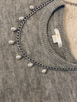 Kedjehalsband med droppformade pärlor - Snyggt halsband med en silverfärgad rostfritt stål kedja och droppformade vita pärlor som hänger längs hela halsbandet. Perfekt accessoar för att lyfta din outfit med en trendig och elegant touch. Passar till många olika stilar och är lätt att matcha.