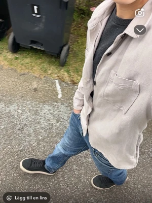 Beige overshirt från Dressmann - Snygg beige overshirt från Dressmann i storlek S. Jackan har en klassisk krage, bröstficka och knäppning med svarta knappar. Tillverkad i mjukt bomullsmaterial, perfekt att slänga på över en t-shirt eller tröja. Enkel och stilren design som funkar till jeans.