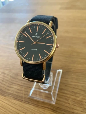 Newport Rose Gold 37mm Damur - Säljer en Newport Quartz-klocka med ett svart tygarmband och boett i roséguld. Klockan har en svart urtavla med roséguldfärgade indexmarkeringar och visare. Den är i gott skick och fungerar felfritt. Behöver bara nytt batteri.  Nypris: 500 SEK Mitt pris: 289 SEK  Skickas alltid snabbt och spårbart. Skriv vid frågor och se gärna mina andra annonser!   GRATIS: För återkommande kunder erbjuder jag personlig experthjälp för dig att göra nya fynd (nytt & begagnat). Fråga för mer info!
