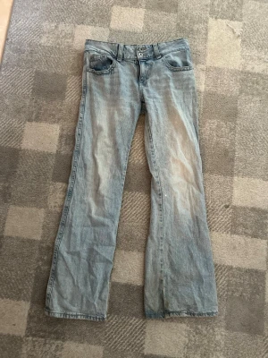 Ljusblå bootcut jeans - Säljer ett par ljusblå bootcut jeans. Jeansen har snygga slitningar framtill och bakfickor med lock och knapp. Perfekta för dig som gillar en avslappnad och trendig look. Dem är från Gina tricot och är i strl 40. 