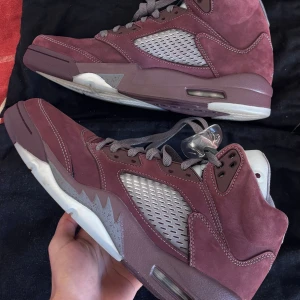 Air Jordan 5 Retro Bordeaux - Snygga Air Jordan 5 Retro sneakers i vinrött mockaskinn med grå meshpaneler och detaljer. Skorna har högt skaft, genomskinlig snörlås och klassisk Jumpman-logga på plösen. Perfekta för dig som vill sticka ut med stilrena och unika sneakers.