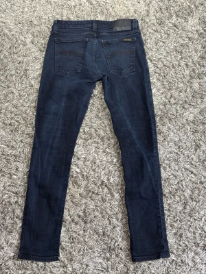 Nudie Jeans - Säljer ett par schyssta Jeans från Nudie Jeans i storlek L30 W29. Jeansen är i en fett mörkblå tvätt och har normal passform. Skriv vid minsta fundering eller önskemål av fler bilder !