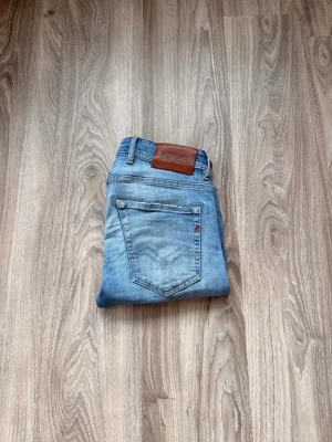 Ljusblå jeans från Replay - Snygga ljusblå jeans från Replay med klassisk femficksdesign och läderpatch bak i midjan. Jeansen har smal passform och är tillverkade i mjukt denimtyg med subtila slitningar för en avslappnad look. Passar oerfekt på mellan 168-175!! Självklart äkta!!