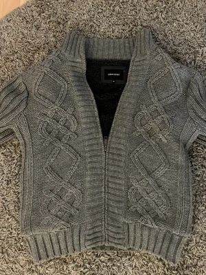 Grå stickad kofta från Urban Spirit - Snygg grå stickad kofta från Urban Spirit med dragkedja framtill. Den i strl M och i nytt skick. Hör av dig om du har några frågor.