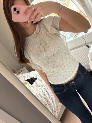 Vit spetsmönstrad topp - Säljer en söt vit topp med spetsmönster och korta ärmar. Toppen har en rund halsringning och är lätt figursydd för en snygg passform. Perfekt att matcha med jeans eller kjol för en fräsch look.