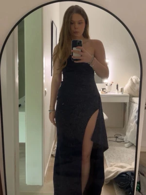 Marinblå balklänning axelbandslös långklänning - Snygg marinblå axelbandslös långklänning med hög slits på ena sidan. Klänningen har en figurnära passform och stilren design, perfekt för speciella tillfällen. Materialet känns mjukt och följsamt mot kroppen.