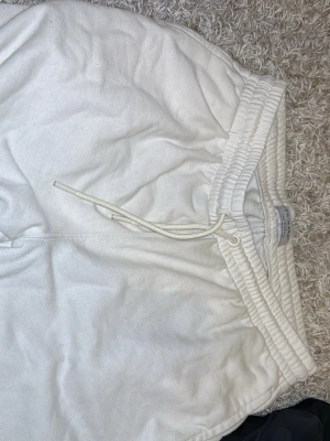 Vita shorts från Primark med snörning - Säljer ett par vita shorts från Primark i storlek Large. De har elastisk midja med snörning för skön passform och är tillverkade i mjukt bomullsmaterial. Perfekta för avslappnade dagar eller träning.