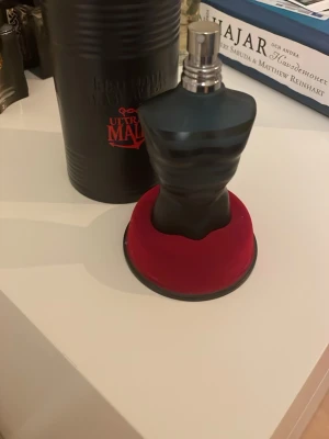 Jean Paul Gaultier Ultra Male parfym - Jean Paul Gaultier Ultra Male Eau de Toilette Intense i en ikonisk svart flaska formad som en manlig torso. Flaskan har mattsvart finish med diskreta ränder och metallisk spraydel. Kommer med originalförpackning i svart metall och röd bas. Ungefär 60% kvar. 