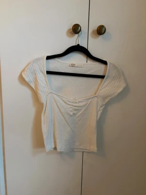 Vit croppad topp - Söt vit croppad topp från Pull&Bear med korta ärmar. Perfekt till sommaren och enkel att matcha med olika stilar.