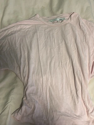 Ljusrosa t-shirt från 157 - En enkel och stilren ljusrosa t-shirt från 157. T-shirten har rund halsringning och korta ärmar. Tillverkad i mjuk bomull som känns skön mot huden. Perfekt basplagg att matcha med jeans eller kjol.