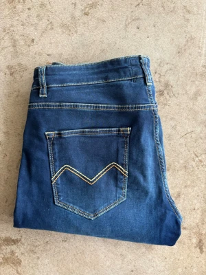 Mörkblå jeans med kontrastsömmar - Snygga mörkblå jeans med raka ben och kontrastsömmar på bakfickan. Klassisk femficksmodell, dom är i storlek 33/34 men sitter som en 31/32