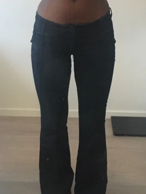 Lowwaist mörkblå bootcut jeans - Säljer ett par mörkblå bootcut jeans med låg midja och klassiska fickor bak. Det är omsydd till lowwaist 