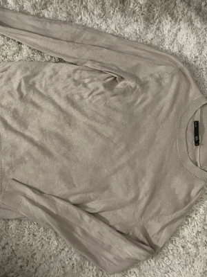 Beige stickad tröja från lager 157 - En stilren beige stickad tröja från lager 157 med rund halsringning och ribbade muddar vid ärmslut och nederkant. Tröjan har en enkel och klassisk design som passar till det mesta. Perfekt för lager på lager och enkel att matcha.