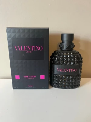 Valentino Uomo Born In Roma EdP - Valentino Uomo Born In Roma EdP är en lyxig parfym i en svart, nitat glasflaska med rosa detaljer. Flaskan har en unik, edgy design och kommer i en matchande svart kartong med rosa text. Doften är intensiv och modern, perfekt för dig som vill sticka ut. Det röda strecket visar vätskenivån.