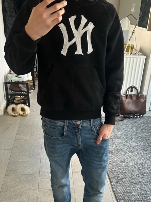 Svart hoodie med vit NY-logga - Fet och unik hoodie från Carhartt med påsytt NY Yankees märke! Strlek: XS (Modellen på bilen är ca 172)
