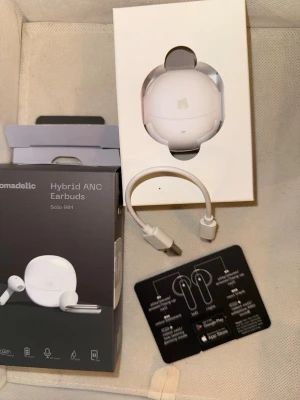 EarPods för iPhone/Android - Helt nya Oanvända EarPods i förpackning som passar iPhone o Android, säljes pga kommer ej användas & fick dessa i julklapp. Skickas med i originalförpackning & allt, endast öppnad för att ta bilder. Nomadelic Hybrid ANC Earbuds Solo 991 i vitt med rund laddningsetui. Trådlösa in-ear hörlurar med aktiv brusreducering, touchkontroller och USB-laddkabel. Snygg och modern design, perfekt för musik och samtal.