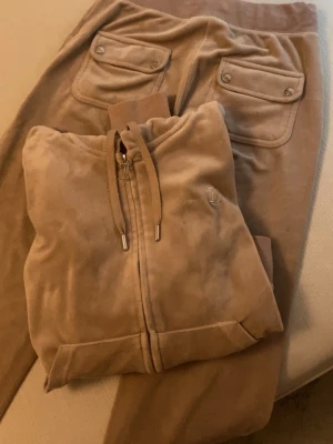 Juicy couture byxor i beige - Byxorna har några märken på bena som inte går bort. Byxorna är i XS tröjan i S